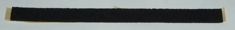 Schwarze Dichtung mit flauschiger Oberfläche, vermutlich für eine Abdeckung, auf einer hellen Unterlage. Teil einer Installation, möglicherweise von Daikin.